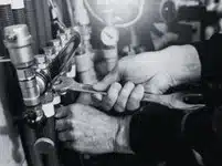 mains utilisant une cle pour ajuster un raccord de plomberie